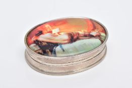 A WHITE METAL OVAL DECORATIVE SNUFF BOX, the enamel panel depicting a lounging half nude lady