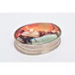 A WHITE METAL OVAL DECORATIVE SNUFF BOX, the enamel panel depicting a lounging half nude lady