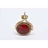A 9CT GOLD SWIVEL FOB, of an oval shape with each side set with carnelian panels, to a scroll