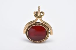 A 9CT GOLD SWIVEL FOB, of an oval shape with each side set with carnelian panels, to a scroll