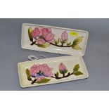 TWO MOORCROFT RECTANGULAR PEN TRAYS, decorated with pink magnolia on a cream ground, impressed and