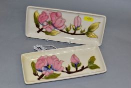 TWO MOORCROFT RECTANGULAR PEN TRAYS, decorated with pink magnolia on a cream ground, impressed and