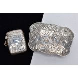 A BELT BUCKLE AND SILVER VESTA, the white metal belt buckle with a wavy edge and decorative floral
