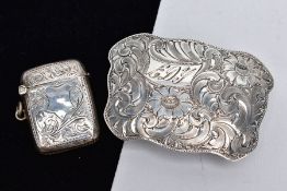 A BELT BUCKLE AND SILVER VESTA, the white metal belt buckle with a wavy edge and decorative floral