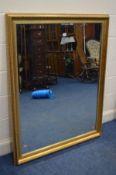 A MODERN GILT FRAMED BEVELLED EDGE WALL MIRROR, 131cm x 105cm