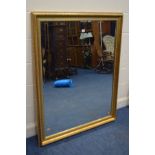 A MODERN GILT FRAMED BEVELLED EDGE WALL MIRROR, 131cm x 105cm