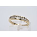 A 9CT GOLD DIAMOND HALF HOOP RING, designed with a row of channel set round brilliant cut