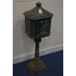 A GREEN PAINTED CAST IRON LETTER BOX on a stand (one bolt missing between base and pillar) (key)