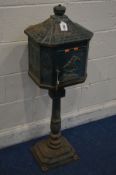 A GREEN PAINTED CAST IRON LETTER BOX on a stand (one bolt missing between base and pillar) (key)