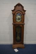 A GOLDEN OAK CHIMING LONGCASE CLOCK, arched glass door enclosing a brassed dial, with automaton