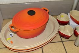A COLLECTION OF LE CREUSET COOKWARE, comprising an orange enamelled cast iron oval casserole, twin