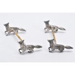 A PAIR OF WHITE METAL KNIFE RESTS, each rest modelled with two foxes to each end with a worn gilt