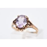 A 9CT GOLD AMETHYST RING, designed with a central claw set, oval cut amethyst within a bead and