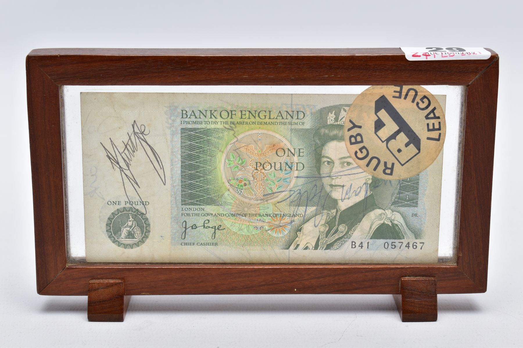 A FRAMED BANK OF ENGLAND 'ONE POUND NOTE', within a wooden frame, raised on two block feet, the note