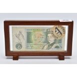 A FRAMED BANK OF ENGLAND 'ONE POUND NOTE', within a wooden frame, raised on two block feet, the note