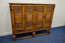 A JAYCEE OAK FOUR DOOR CUPBOARD with fielded panels between floral carved panels, enclosing three