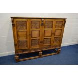 A JAYCEE OAK FOUR DOOR CUPBOARD with fielded panels between floral carved panels, enclosing three