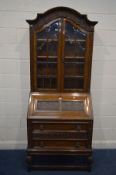 AN EARLY 20TH CENTURY OAK BUREAU BOOKCASE, with elaborate fruiting vine and grape detail, the arched