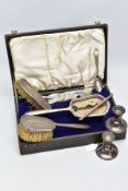 A CASED SILVER VANITY SET WITH TWO CANDLE STICKS AND A TEASPOON, the brown case opens to reveal a