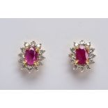 A PAIR OF 18CT GOLD RUBY AND DIAMOND CLUSTER EARRINGS, each designed with a central claw set, oval