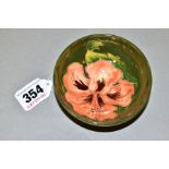 A SMALL FOOTED MOORCROFT POTTERY BOWL, 'Coral Hibiscus' pattern on green ground, impressed