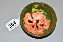 A SMALL FOOTED MOORCROFT POTTERY BOWL, 'Coral Hibiscus' pattern on green ground, impressed