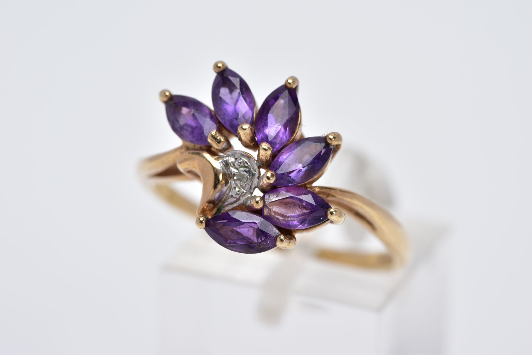 A 9CT GOLD AMETHYST RING, designed as a spray of marquise cut amethyst with a single cut diamond