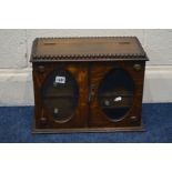 AN EARLY TO MID 20TH CENTURY OAK TWO DOOR SMOKERS CABINET, with oval bevelled glass panels, width