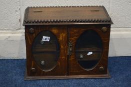 AN EARLY TO MID 20TH CENTURY OAK TWO DOOR SMOKERS CABINET, with oval bevelled glass panels, width