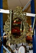 A LATE VICTORIAN PIERCED BRASS FRAMED WALL MIRROR, with masked design holding brass swing candle