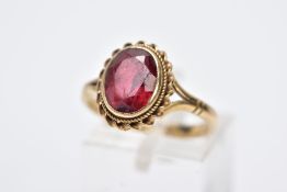 A 9CT GOLD GEMSET RING, designed with an oval red stone assessed as tourmaline, within a collet