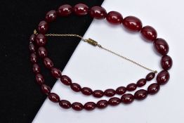 A CHERRY AMBER BAKELITE BEAD NECKLACE, designed with a row of forty graduated cherry red oval beads,