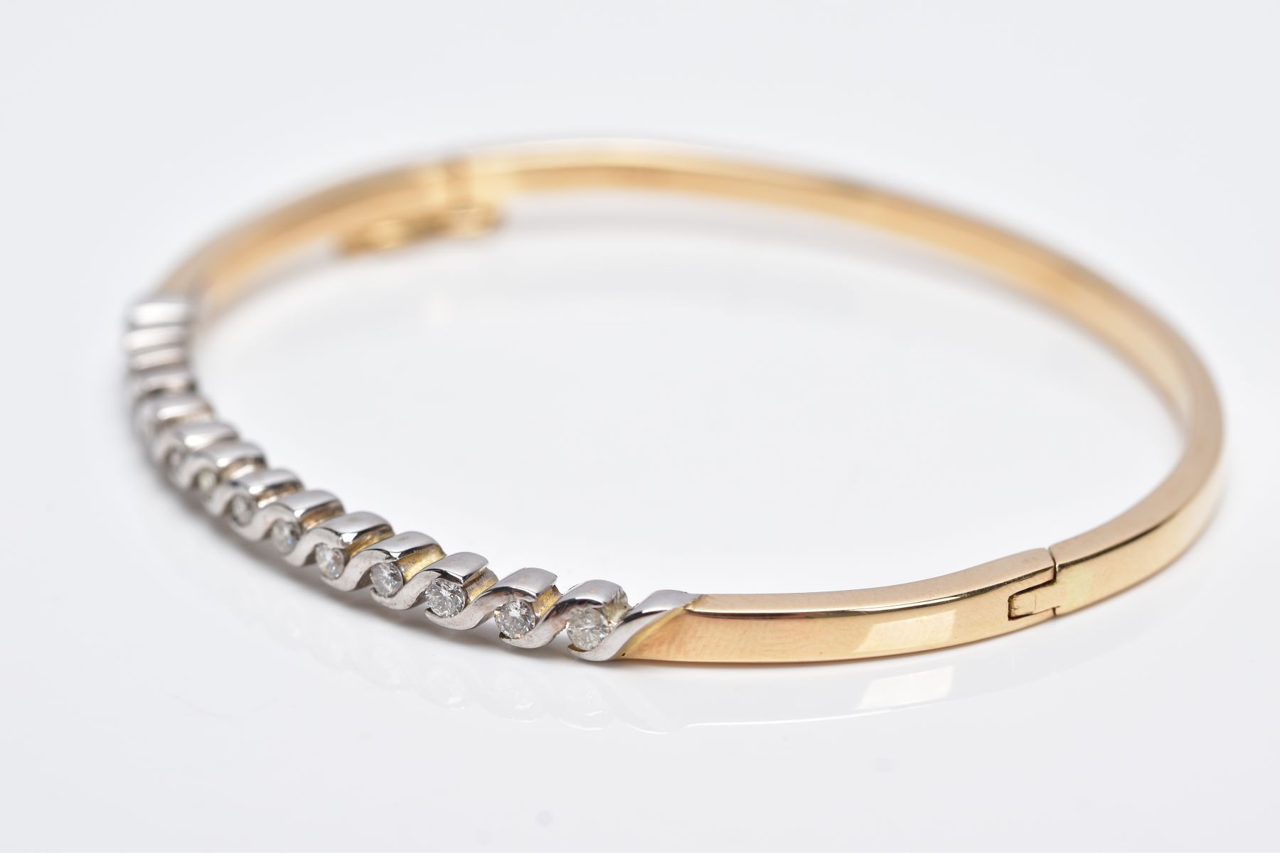 A YELLOW METAL DIAMOND BANGLE, the hinged bangle designed with a row of crossover mounted round - Image 3 of 6