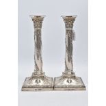 A PAIR OF EDWARDIAN REVIVAL SILVER CANDLESTICKS, each column embossed with oak leaf wreaths, on