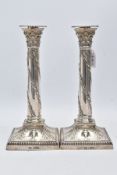 A PAIR OF EDWARDIAN REVIVAL SILVER CANDLESTICKS, each column embossed with oak leaf wreaths, on