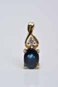 A YELLOW METAL SAPPHIRE AND DIAMOND DROP PENDANT, designed with an oval cut claw set blue