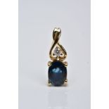 A YELLOW METAL SAPPHIRE AND DIAMOND DROP PENDANT, designed with an oval cut claw set blue