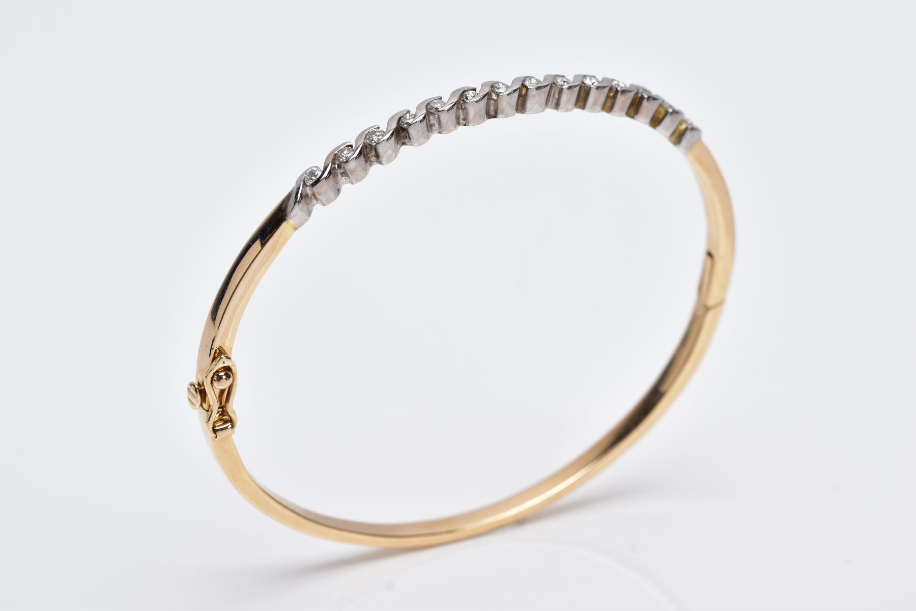 A YELLOW METAL DIAMOND BANGLE, the hinged bangle designed with a row of crossover mounted round - Image 6 of 6