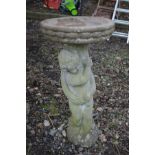 A CIRCULAR COMPOSITE BIRD BATH on a separate support in the shape of a putto, diameter 39cm x height