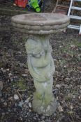 A CIRCULAR COMPOSITE BIRD BATH on a separate support in the shape of a putto, diameter 39cm x height