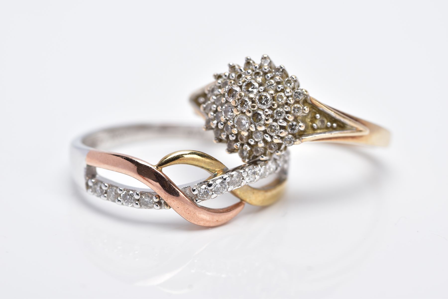 TWO 9CT GOLD DIAMOND RINGS, the first designed as a raised cluster set with round brilliant cut