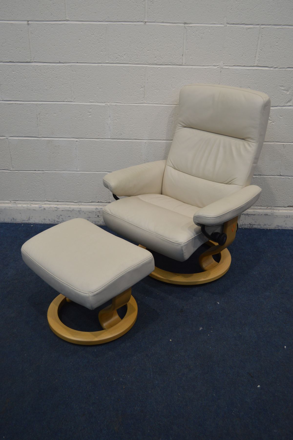 A CREAM EKORNES STRESSLESS SWIVEL RECLINING ARMCHAIR, on a beech frame, along with a matching