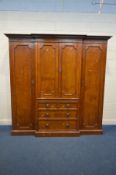 AN EARLY 20TH CENTURY OAK BREAKFRONT FOUR DOOR COMPACTUM WARDROBE, with a moulded cornice with a