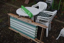 A WHITE PLASTIC CIRCULAR GARDEN TABLE with a parasol, stand and four matching chairs together with