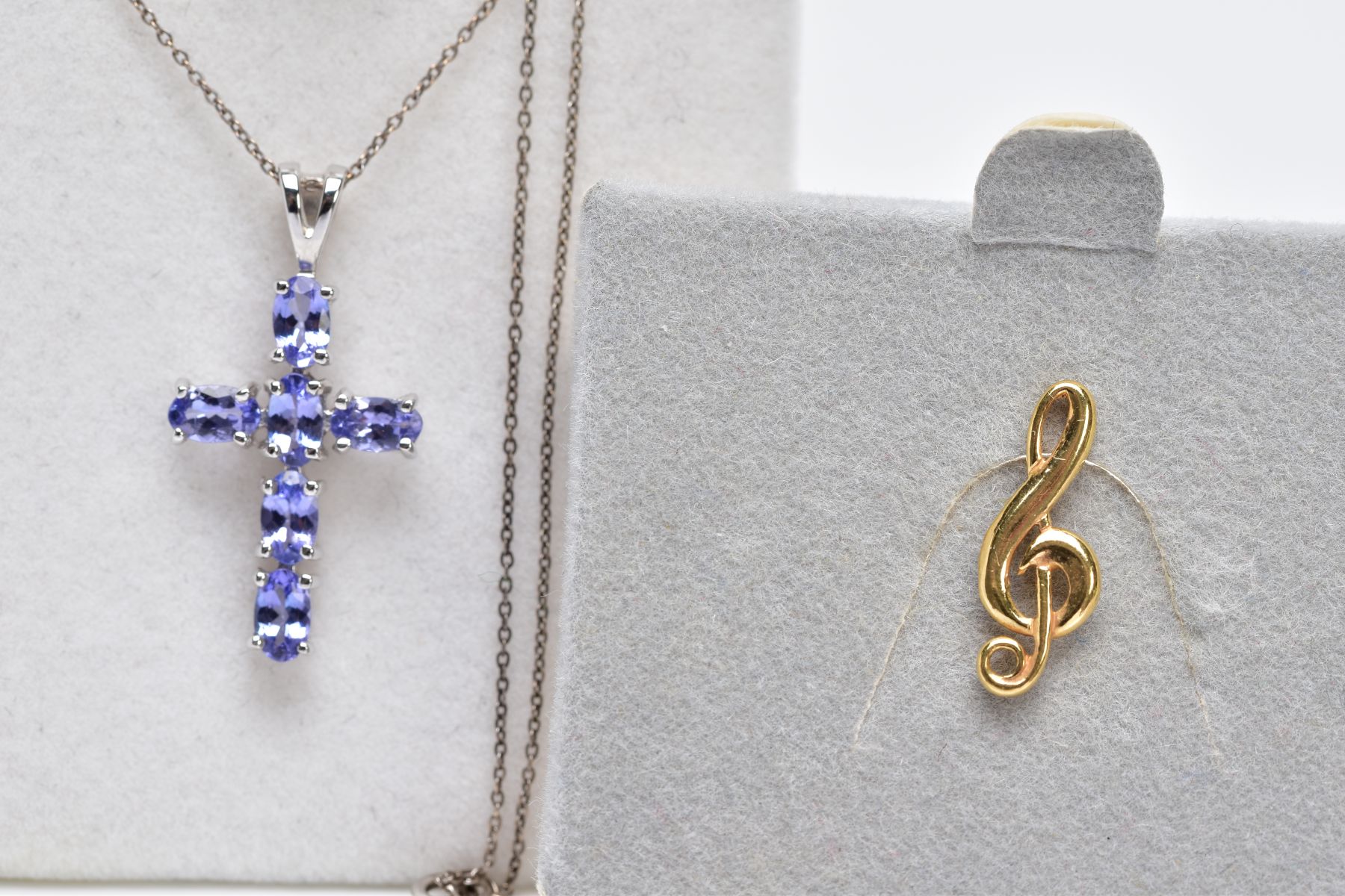 A WHITE METAL CROSS PENDANT NECKLACE AND A TIE PIN, the cross pendant set with six oval cut pale
