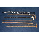 A BUNDLE OF SIX LATE VICTORIAN/20TH CENTURY WALKING STICKS/CANES AND AN UMBRELLA, including a