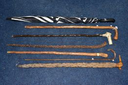 A BUNDLE OF SIX LATE VICTORIAN/20TH CENTURY WALKING STICKS/CANES AND AN UMBRELLA, including a