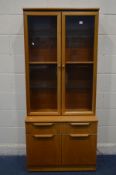 A STONEHILL TEAK GLAZED DOUBLE DOOR BOOKCASE, above a single drawer and double cupboard doors, width