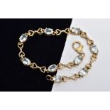 A YELLOW METAL GEM SET LINE BRACELET, designed with nine claw set oval cut colourless stones,