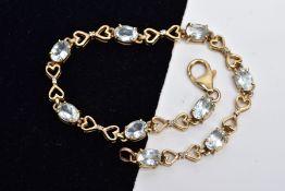 A YELLOW METAL GEM SET LINE BRACELET, designed with nine claw set oval cut colourless stones,